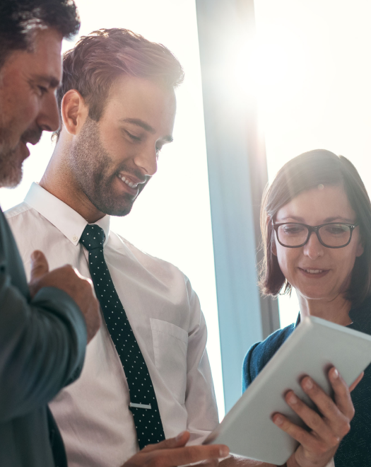 stock-photo-group-of-businesspeople-using-a-digital-tablet-together-in-front-of-office-building-windows-522883786 1