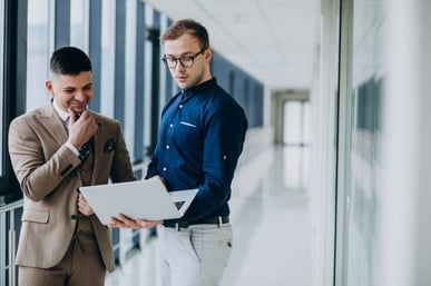 two-male-colleagues-office-standing-with-laptop_1303-19628